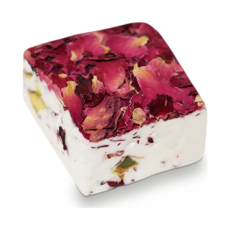 A square of white nougat topped with dried rose petals and pistachios